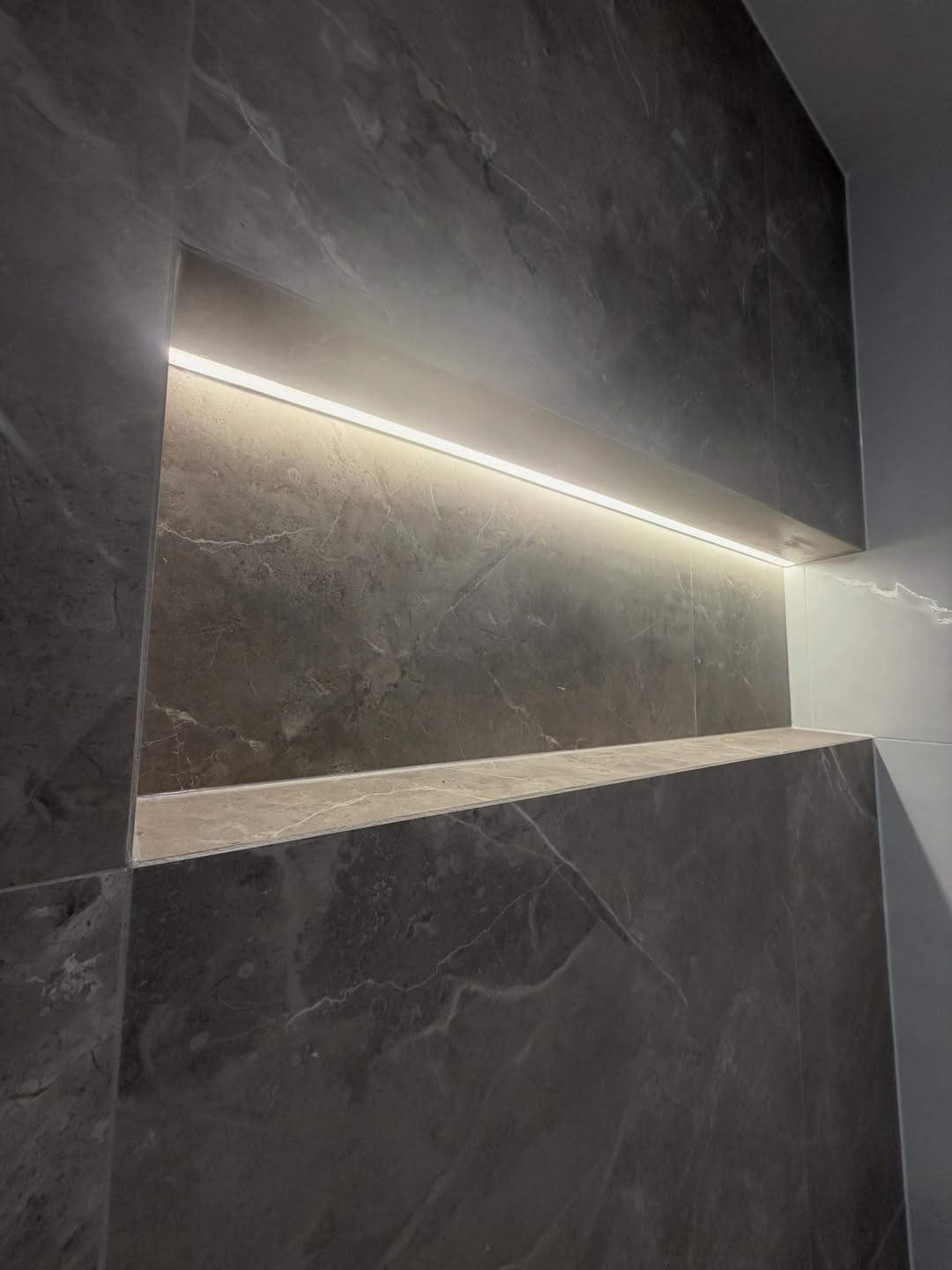 Close-up of a backlit tiled shower niche