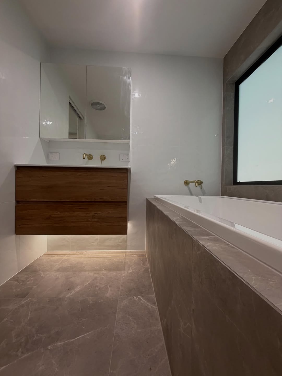 Floating timber vanity with brass wall-mounted tapware