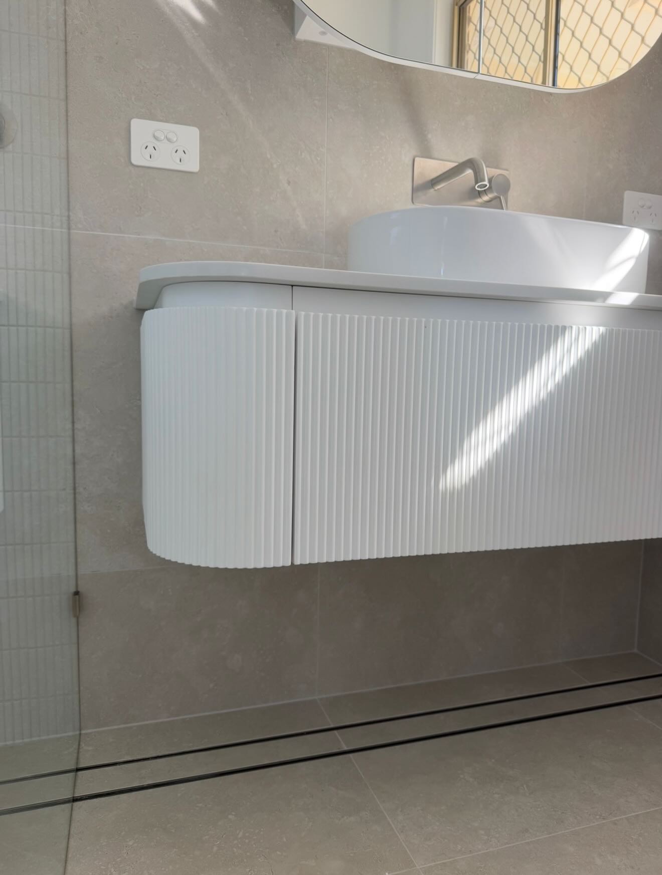 Floating ribbed white vanity with a vessel sink and brushed-nickel tap