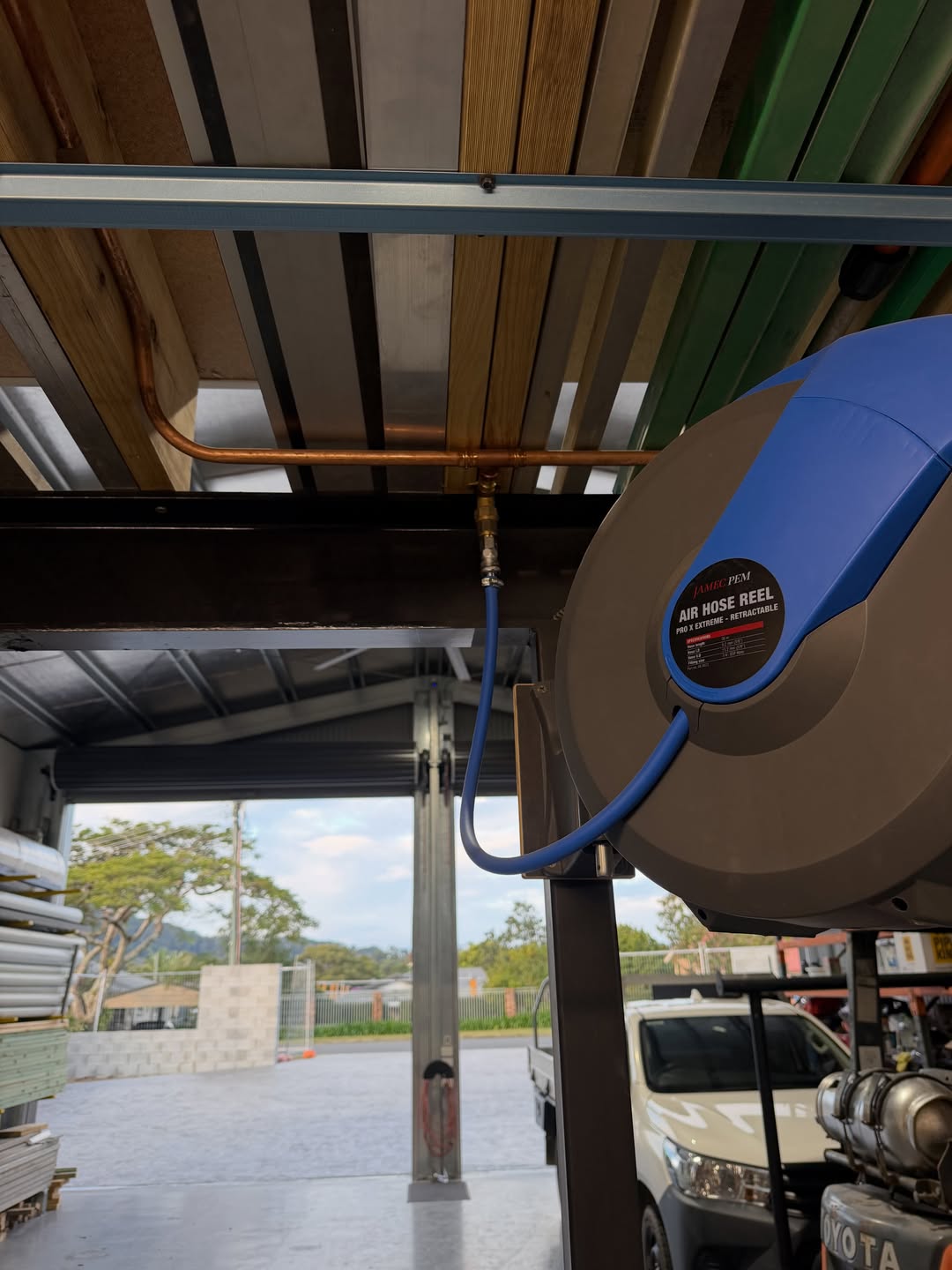 Retractable air hose reel with copper pipe installed under a commercial shed roofline