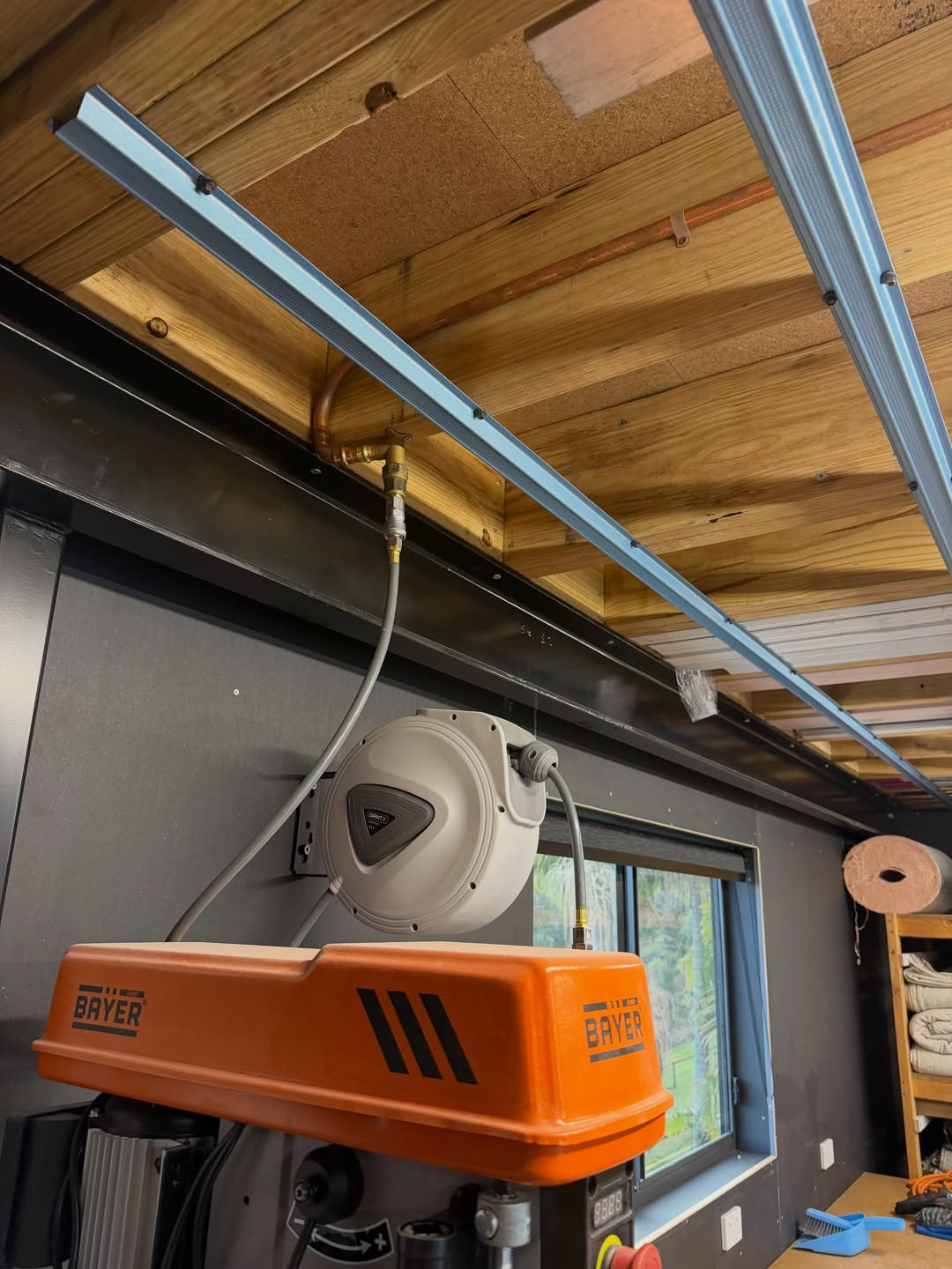 Overhead hose reel installed above a workshop drill press