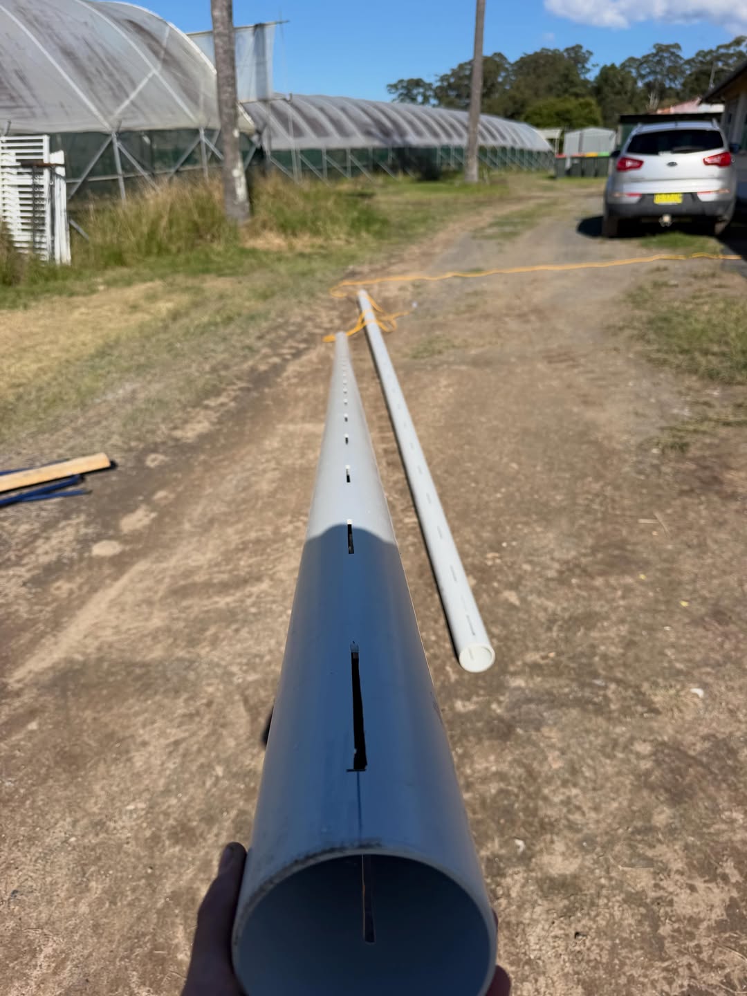 Second view of slotted PVC pipe laid out near greenhouses at the Lowanna property