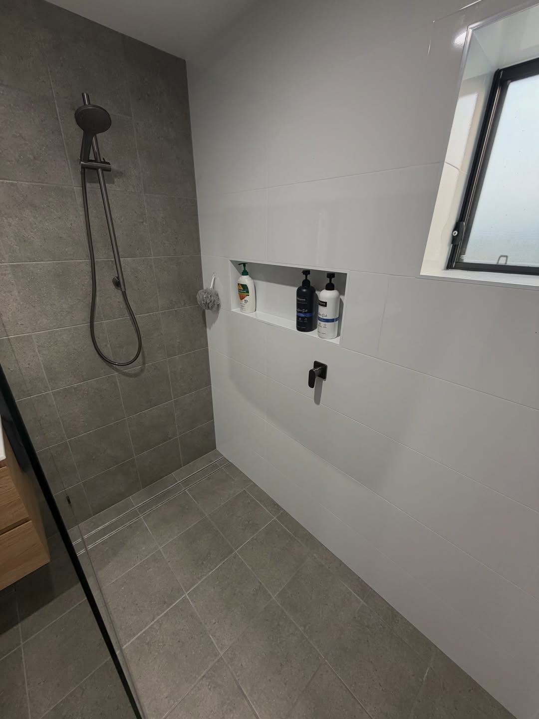 Close-up of a finished tiled shower niche with toiletries